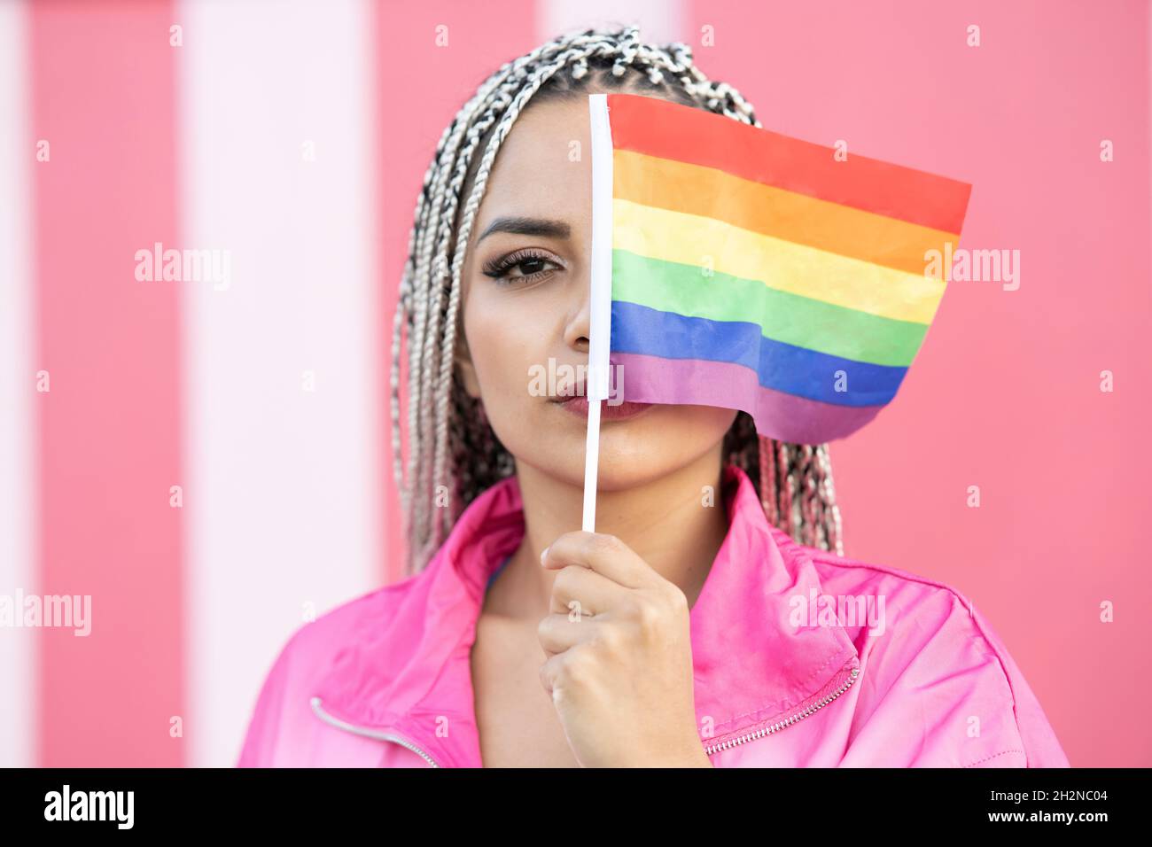 Woman holding rainbow flag in front of pink wall Stock Photo - Alamy