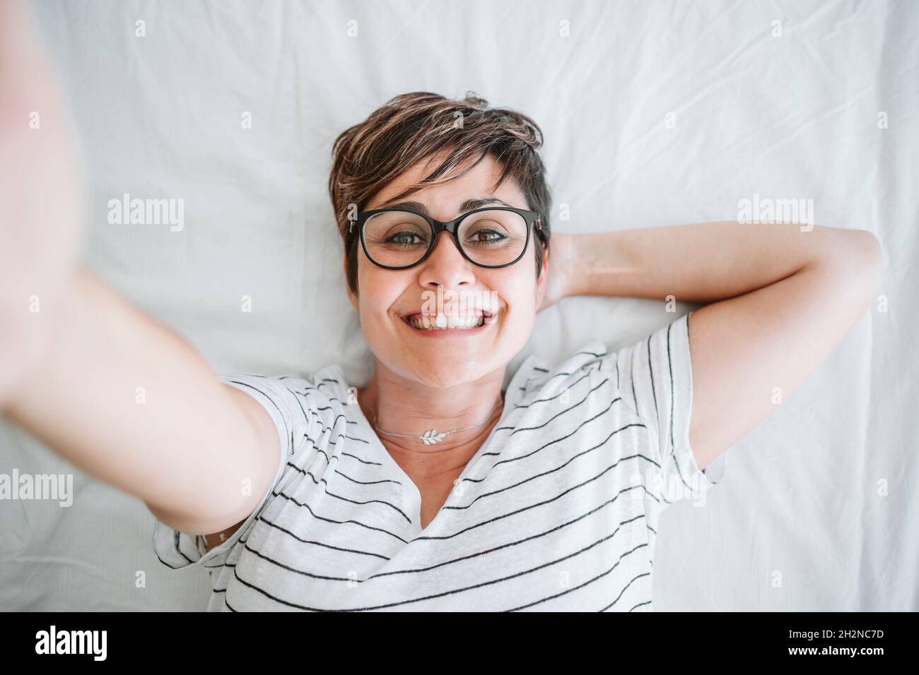 Woman taking selfie while lying on bed Stock Photo