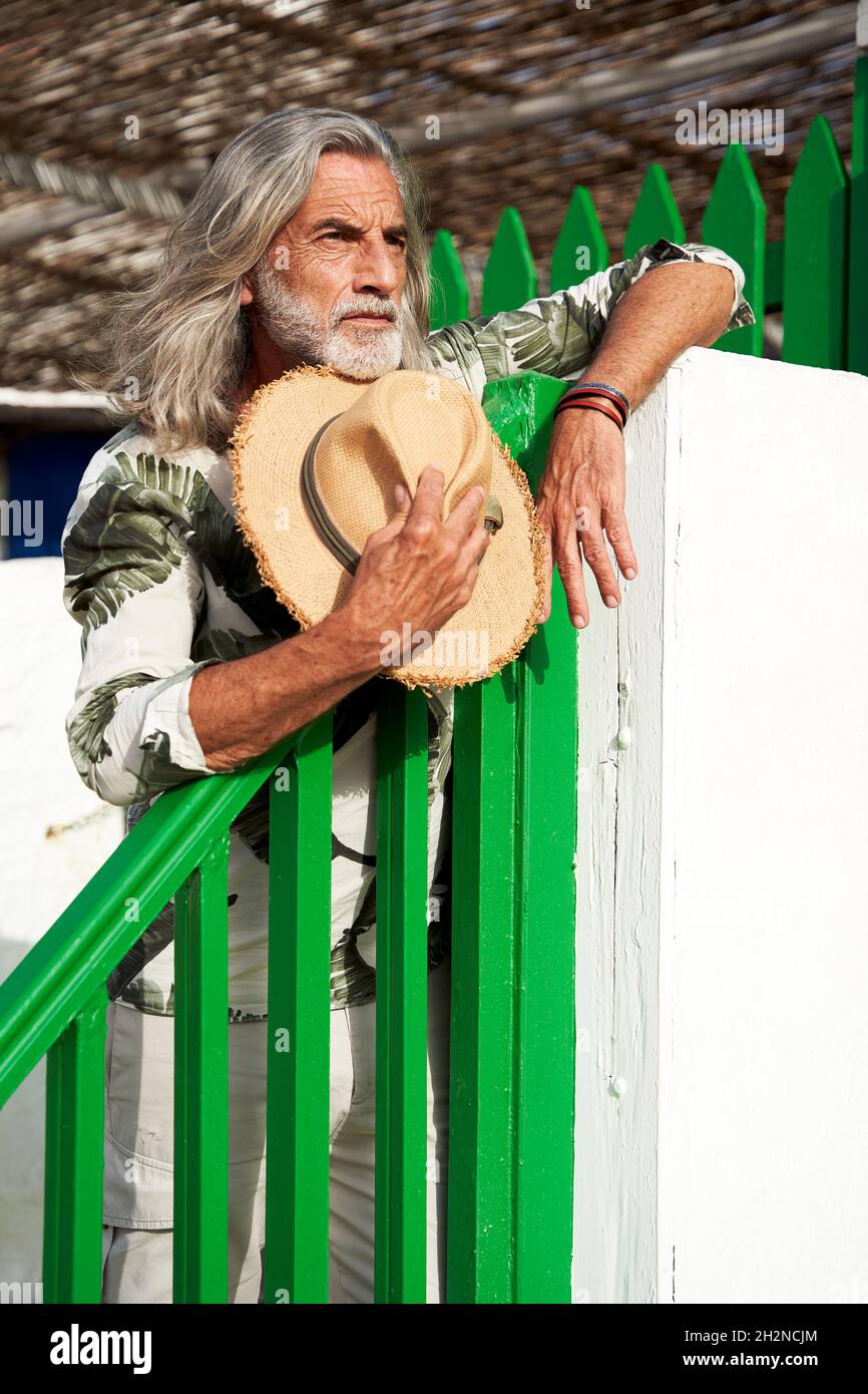 Bearded man with sun hat leaning on railing Stock Photo