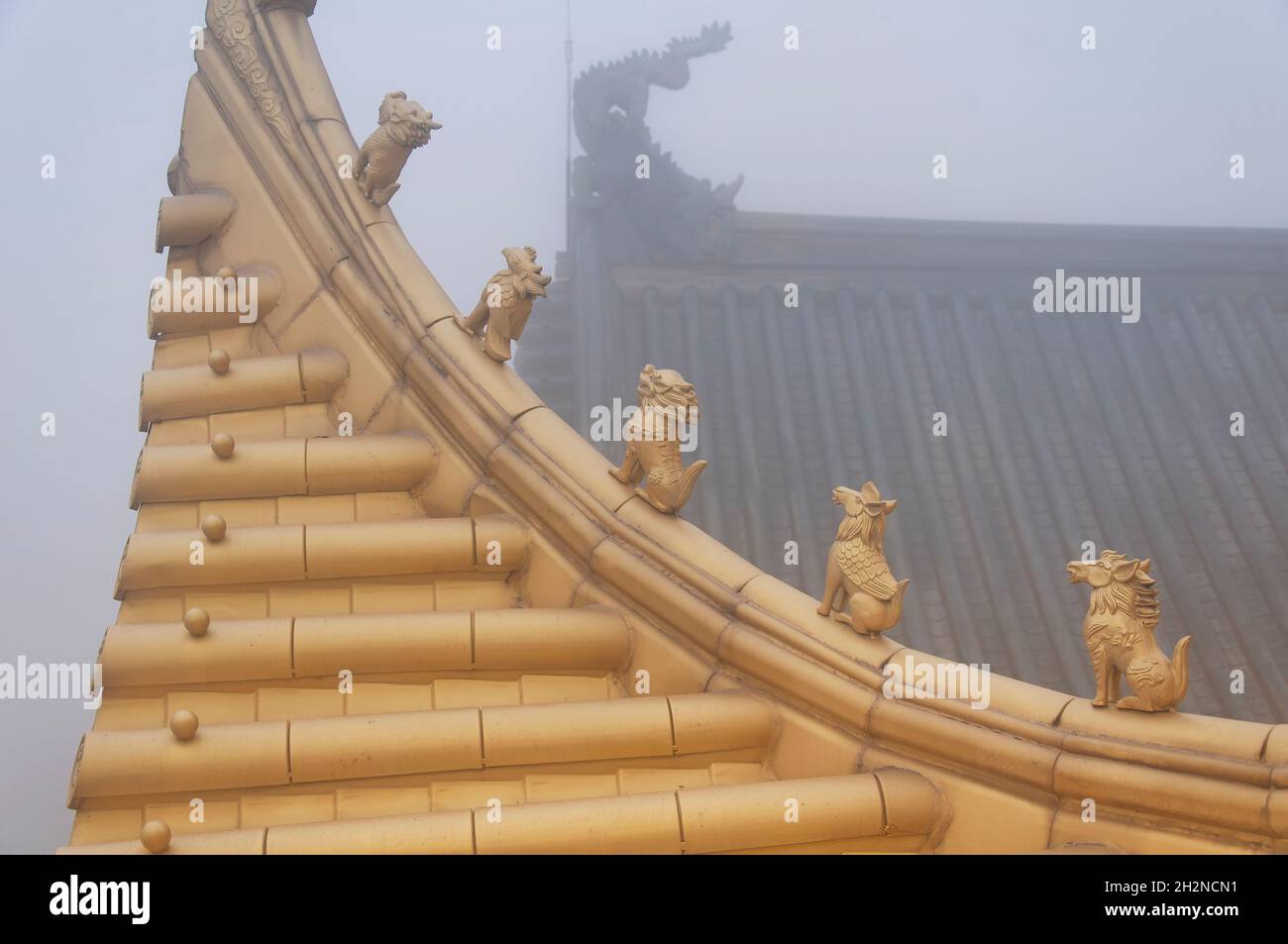 Small mythical creatures atop the buddhist golden hall on a foggy evening on emeishan in sichuan province china. Stock Photo