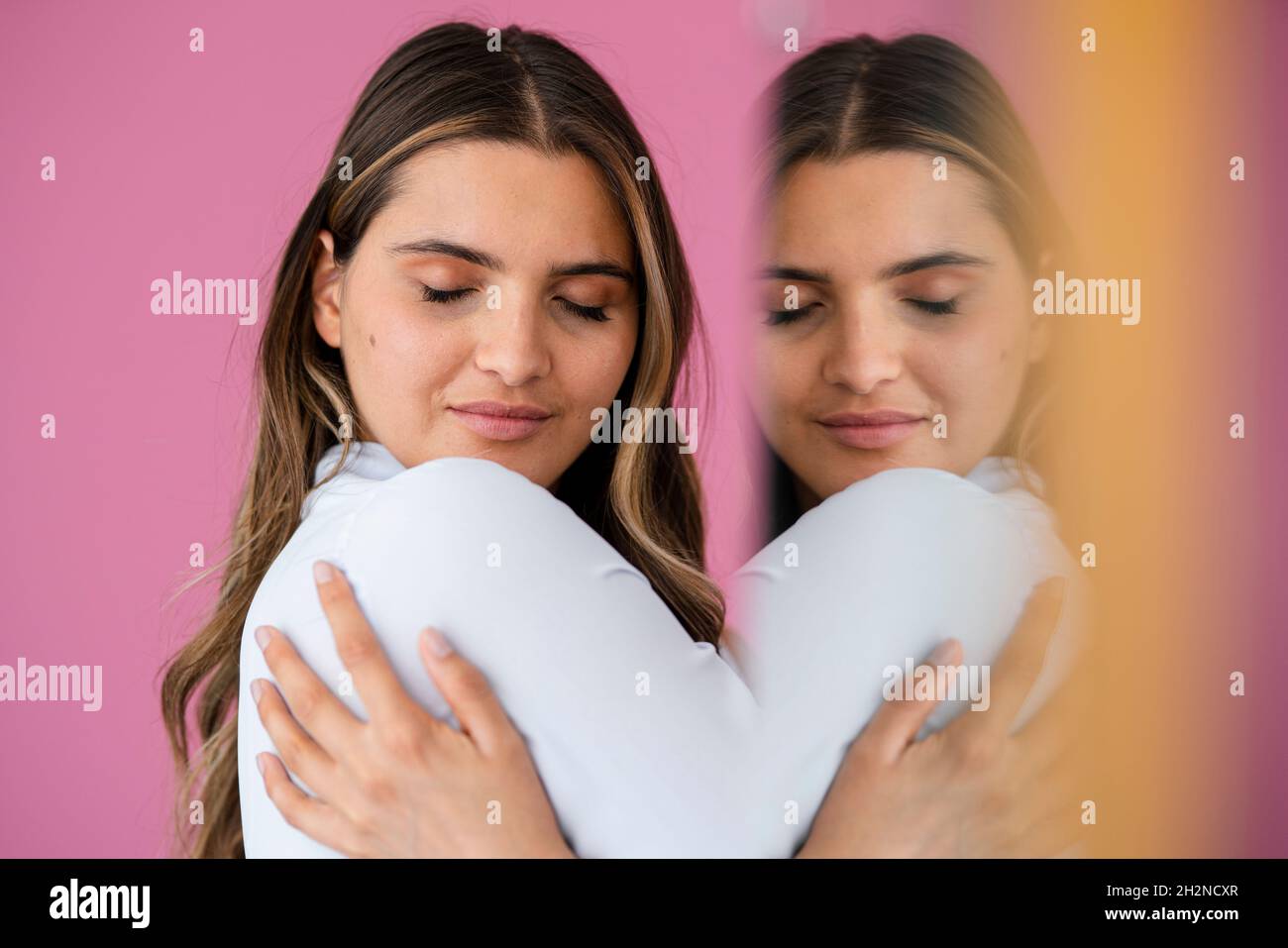 Young female professional hugging self by pink wall Stock Photo