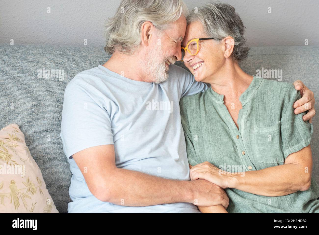 Happy couple sitting on sofa at home Stock Photo