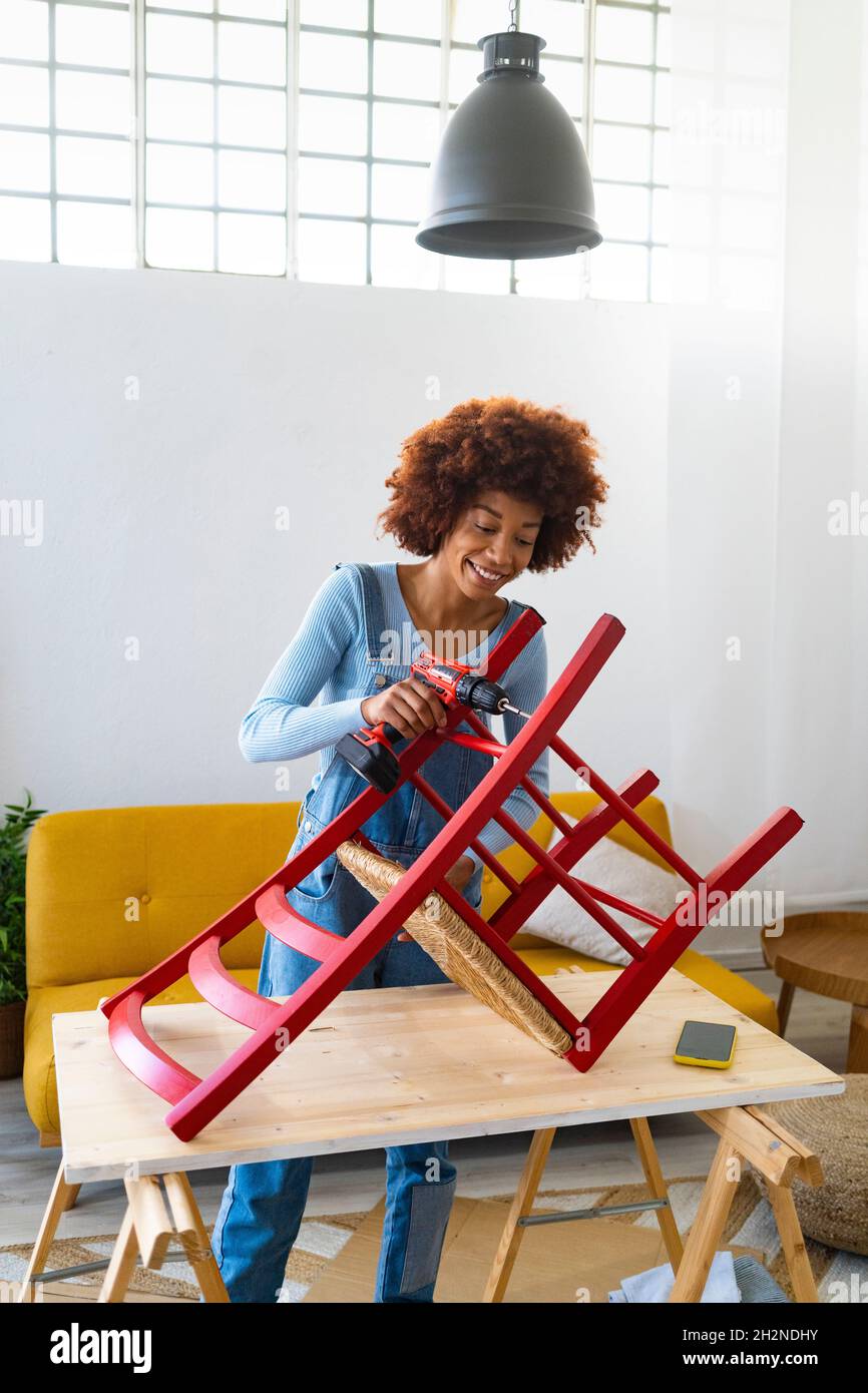 Afro woman restoring wooden chair on table at home Stock Photo