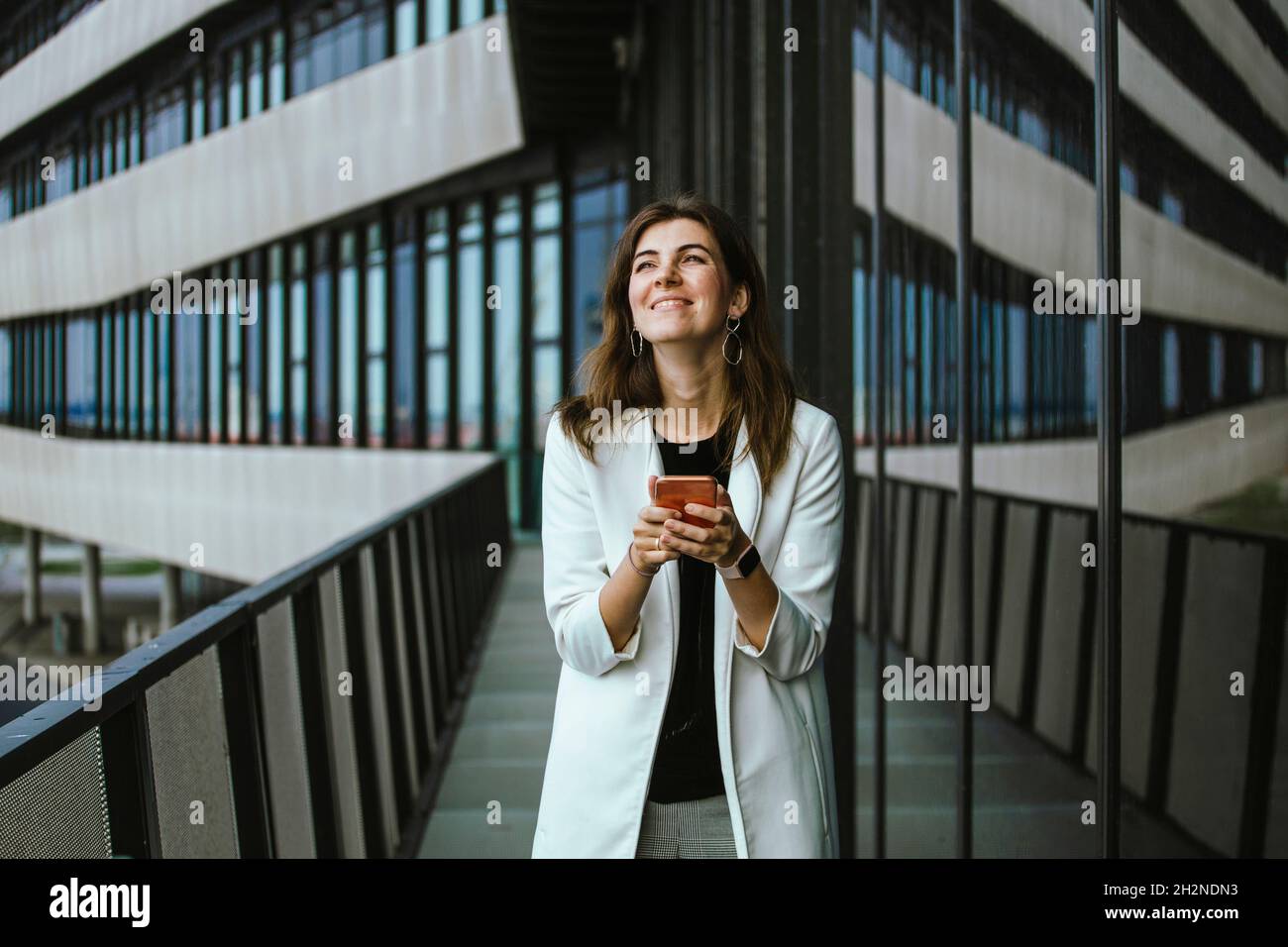 Smiling female professional text messaging through mobile phone Stock Photo