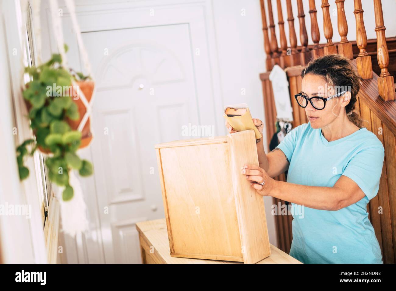 Female craftsperson sanding wood at home Stock Photo