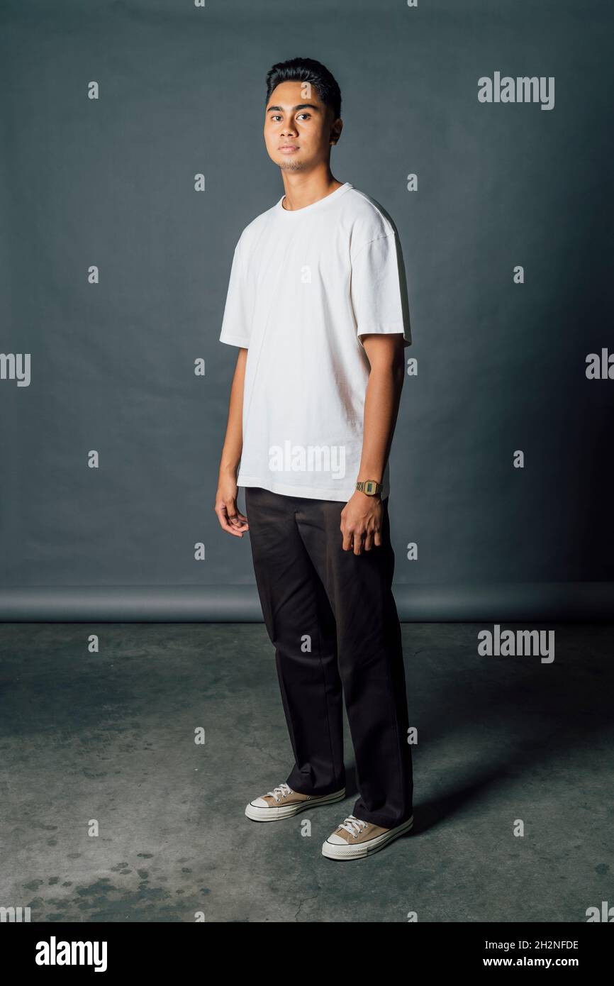 Confident young man standing in front of gray backdrop in studio Stock ...