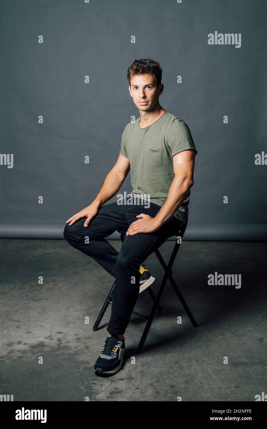 Young man sitting on chair in studio Stock Photo