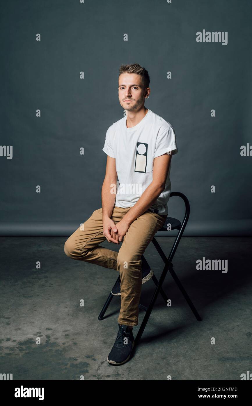 Young man sitting on chair in studio Stock Photo