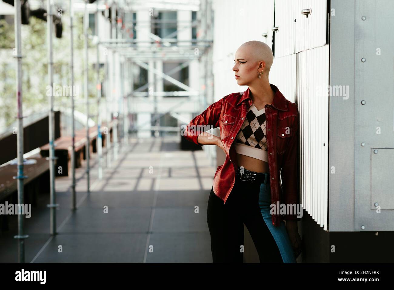 Smiling young bald woman leaning on wall Stock Photo