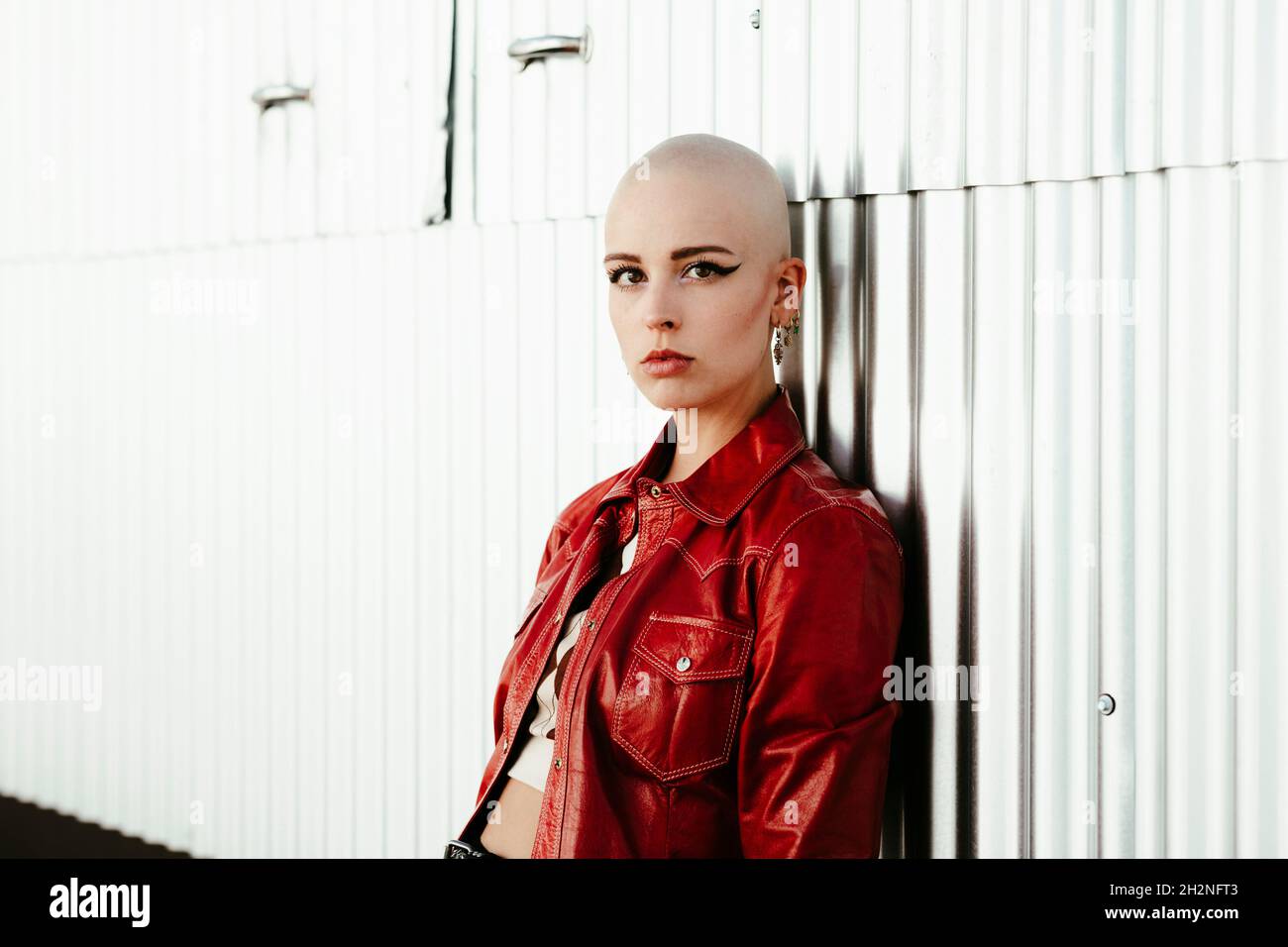 Young bald woman by wall Stock Photo
