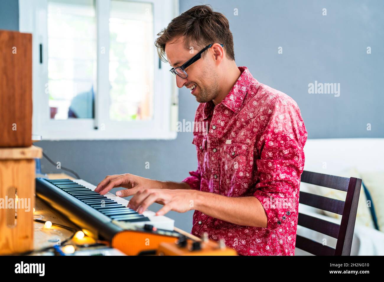 Smiling man with eyeglasses playing piano at home Stock Photo