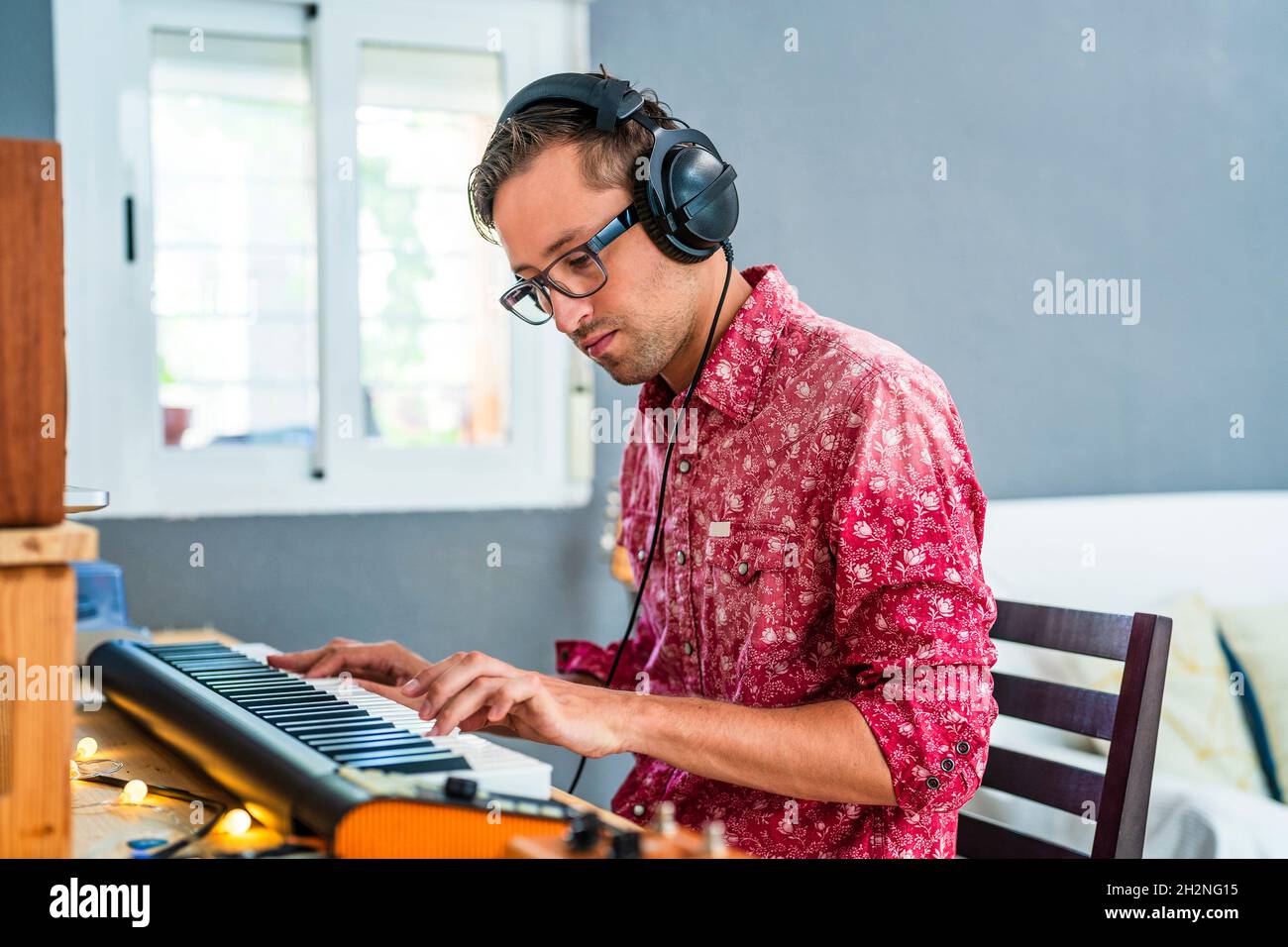 Male musician wearing headphones while playing piano at home Stock Photo