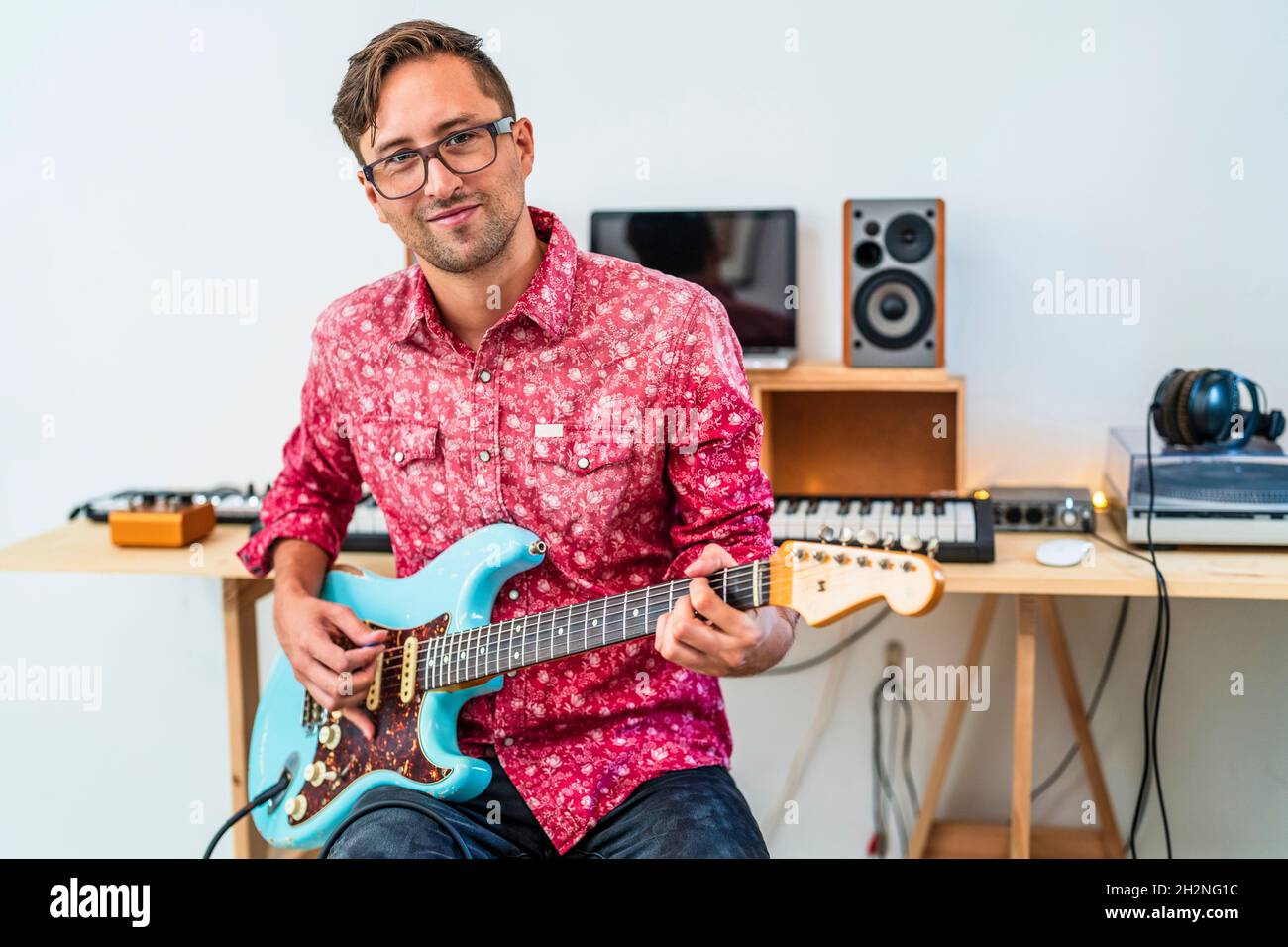 Male musician playing guitar while sitting at home Stock Photo