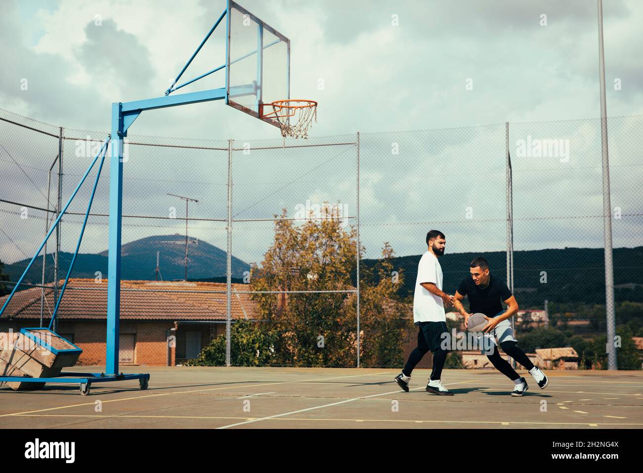 Man defending ball while playing basketball with friend at sports court Stock Photo