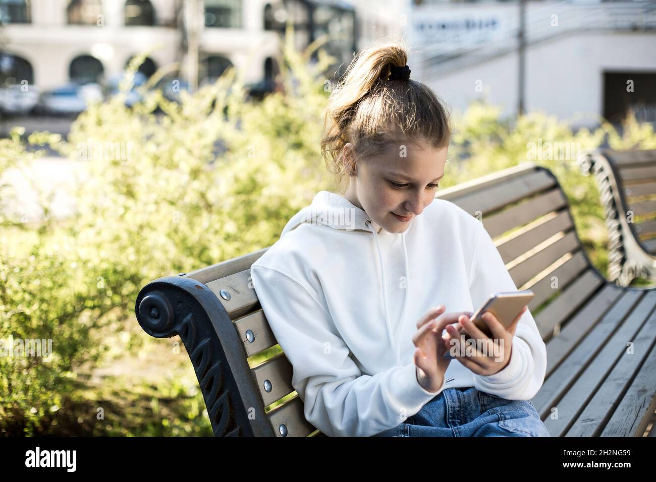Girl using smart phone while sitting on bench Stock Photo