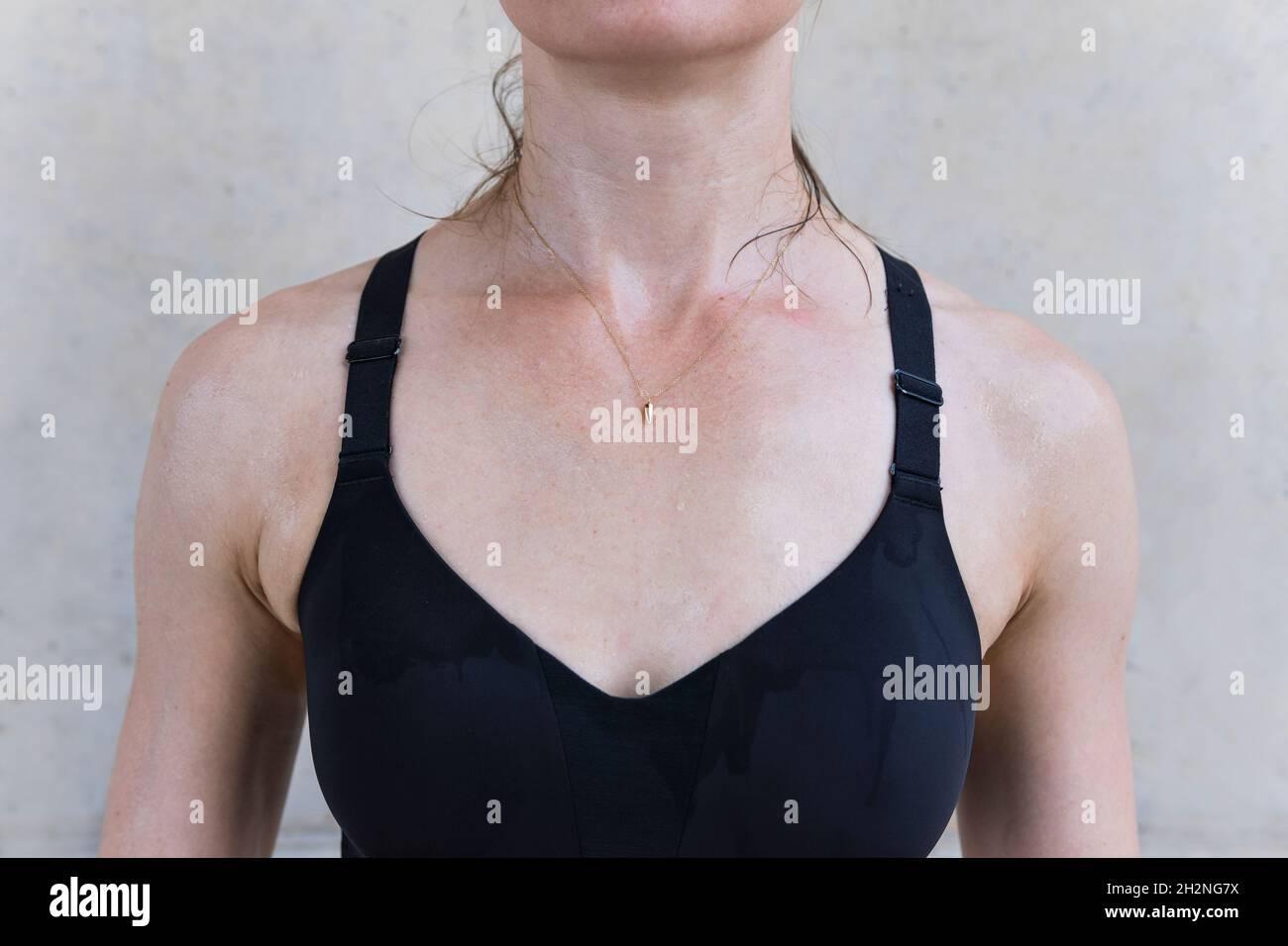 Female athlete wearing sports bra in front of wall Stock Photo