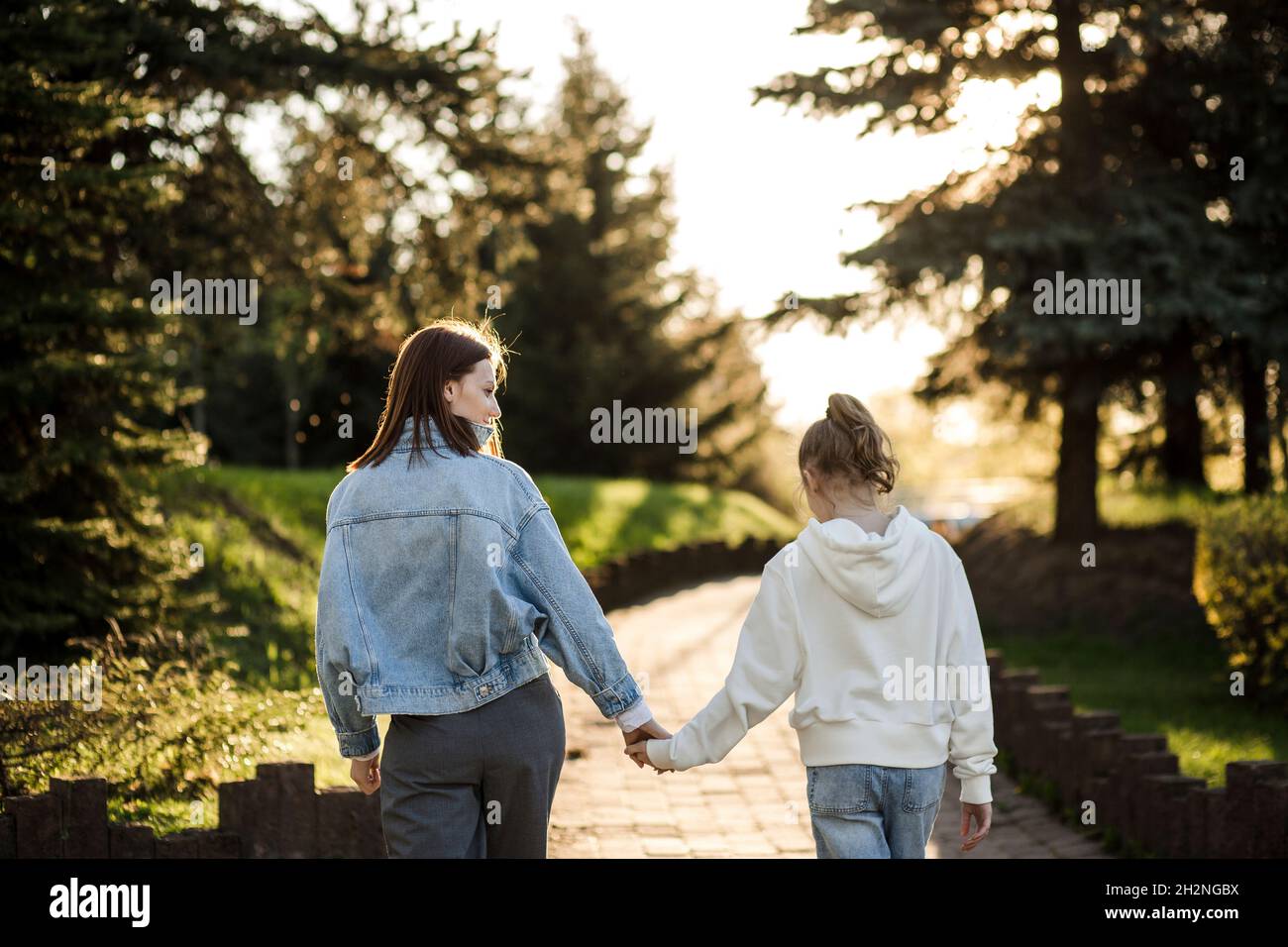 Mother and daughter holding hands while walking in park Stock Photo - Alamy