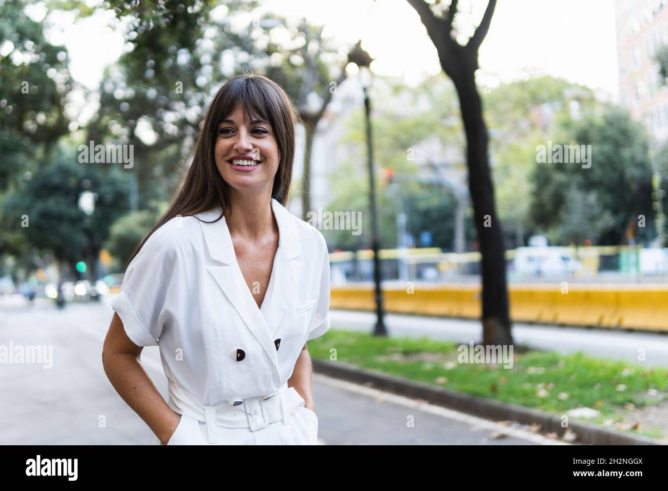 Happy woman with hands in pockets standing on road Stock Photo - Alamy