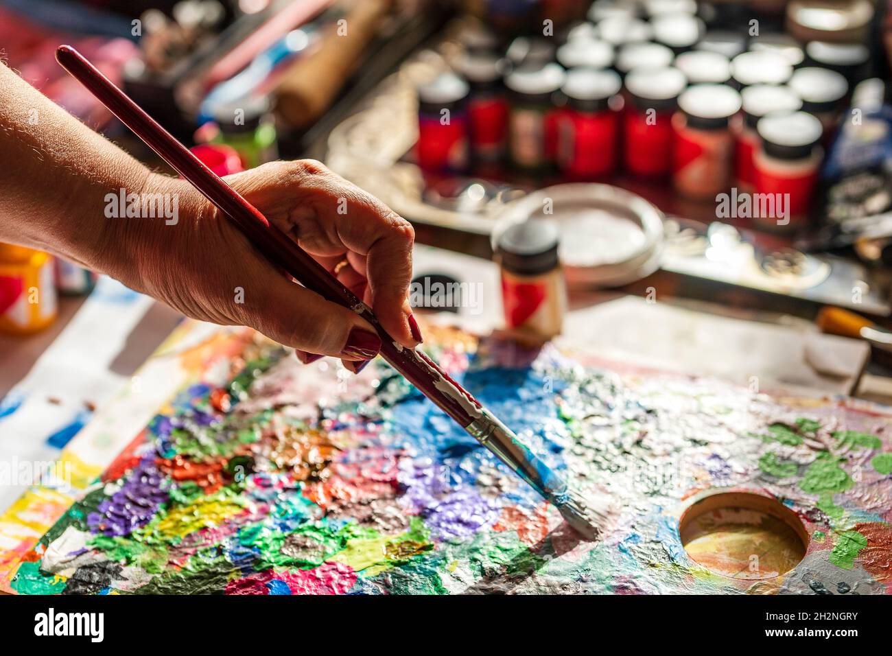 Woman mixing paint with brush on palette Stock Photo