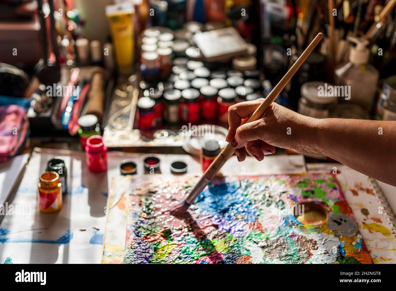 Woman holding paint brush while mixing paint on palette Stock Photo