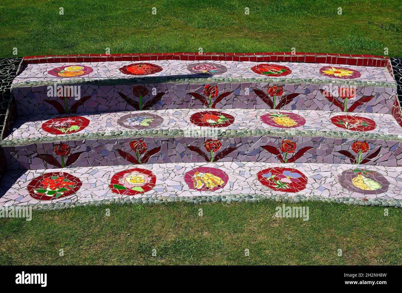 3 mosaic steps, ceramic tile fragments, flower motif, colorful, creative, grass, garden, artistic, The Giants House, Akaroa; New Zealand Stock Photo