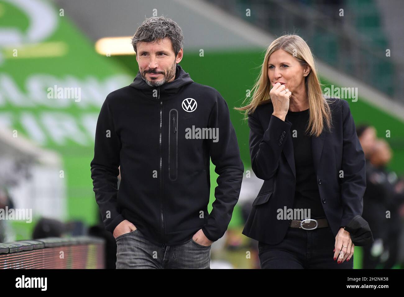Wolfsburg, Germany. 23rd Oct, 2021. Football: Bundesliga, VfL Wolfsburg - SC Freiburg, Matchday 9 at the Volkswagen Arena. Wolfsburg coach Mark van Bommel is in the stadium with VfL press officer Barbara Ertel-Leicht before the match. Credit: Swen Pförtner/dpa - IMPORTANT NOTE: In accordance with the regulations of the DFL Deutsche Fußball Liga and/or the DFB Deutscher Fußball-Bund, it is prohibited to use or have used photographs taken in the stadium and/or of the match in the form of sequence pictures and/or video-like photo series./dpa/Alamy Live News Stock Photo