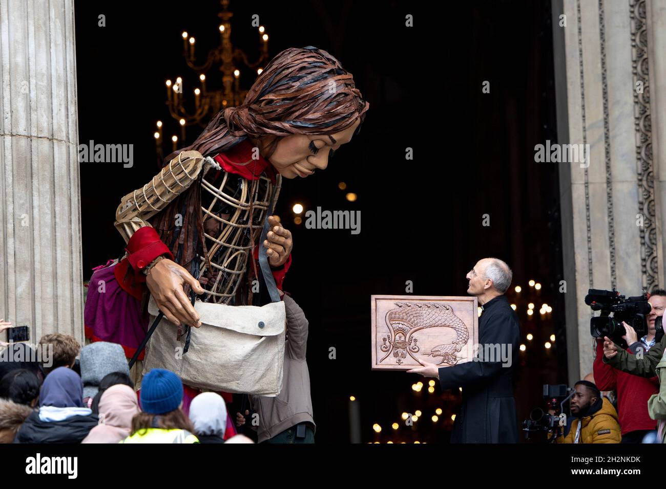 The Pastor from the St Paul Cathedral receives the token of appreciation from the Little Amal.Little Amal, a 3.5 meters tall puppet portrayed as a 9 year old Syrian refugee girl and representing all refugee children, arrived central London at the Great Door of the St Paul Cathedral. She has been on journey since July this year departing from the Syrian-Turkish border in search of her 'mother'.  She will walk 8000 km and arrive at Manchester in early November as her final destination, where it is also the location of the short term holding facility for refugees in the UK. (Photo by Hesther Ng / Stock Photo