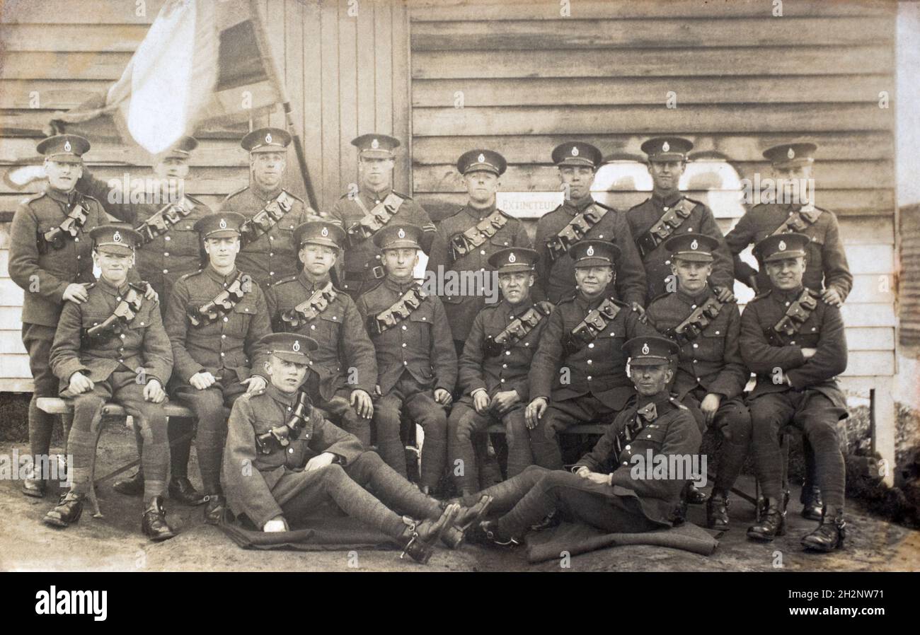 An inter-war era group potrait of British soldiers, signalers in the Royal Corps of Signals, c.1920s, outside a barracks hut with a guidon style troop flag. Many of the soliders have spurs and reinforced riding trousers, indicting they are a mounted unit of signalers. Stock Photo