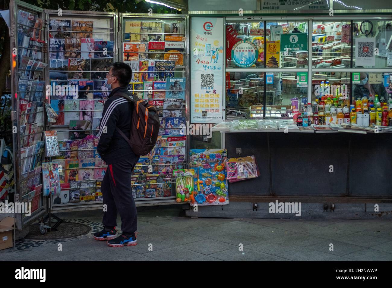 A young man looks at magazines in a newsstand in Beijing, China. 23-oct-2021 Stock Photo