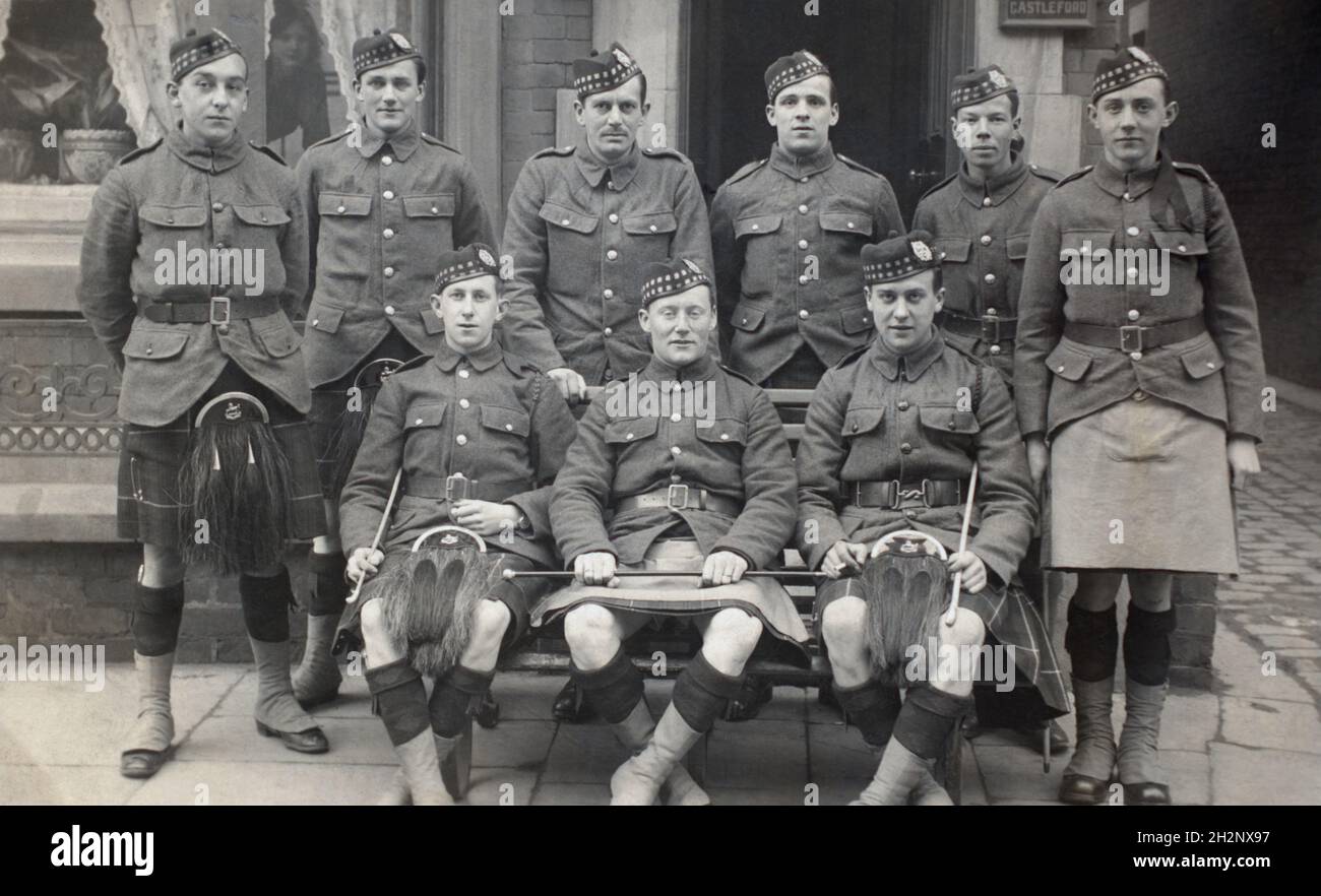 A First World War era group picture of nine kilted soldiers from the Liverpool Scottish, the 10th battalion of the  King's (Liverpool) Regiment. One of the four men standing in the back row is described as having seen service in German East Africa (although the battalion itself did not). Two of thestanding men are described as drafts due to leave for 'the front' in the next week. Others in the group are described as rookies. One of the soliders is named Frank. There is a sign saying 'Casteford' suggesting the picture was taken in Yorkshire. A woman looks out from the window. Dated 22/04/1916. Stock Photo