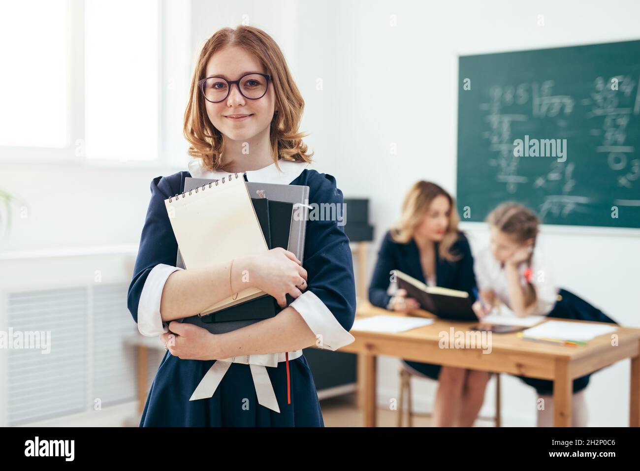 Portrait of smiling school girl with books in classroom Stock Photo - Alamy