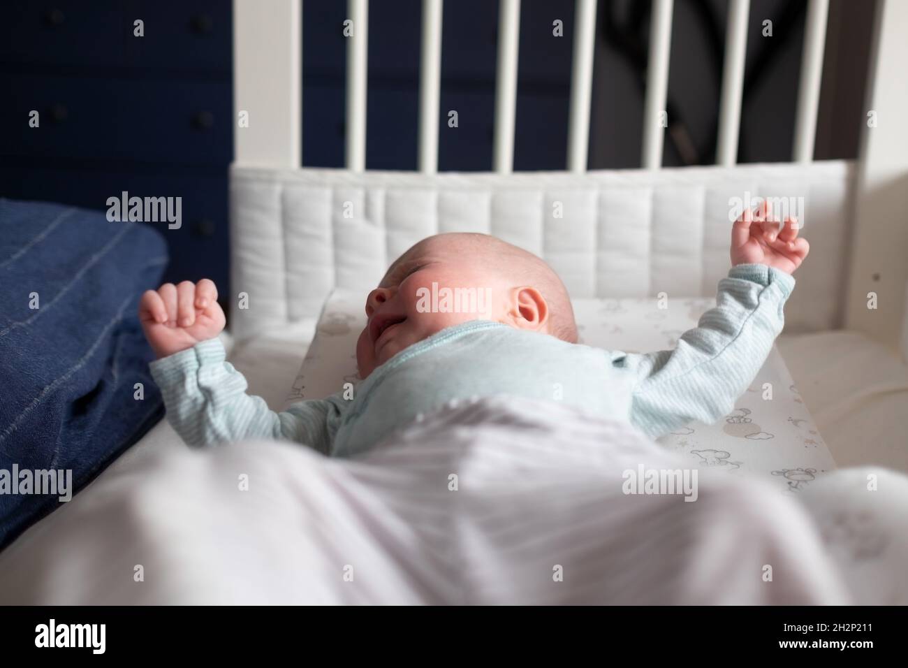 Crying caucasian baby on a bed suffering from colic pain. Stock Photo