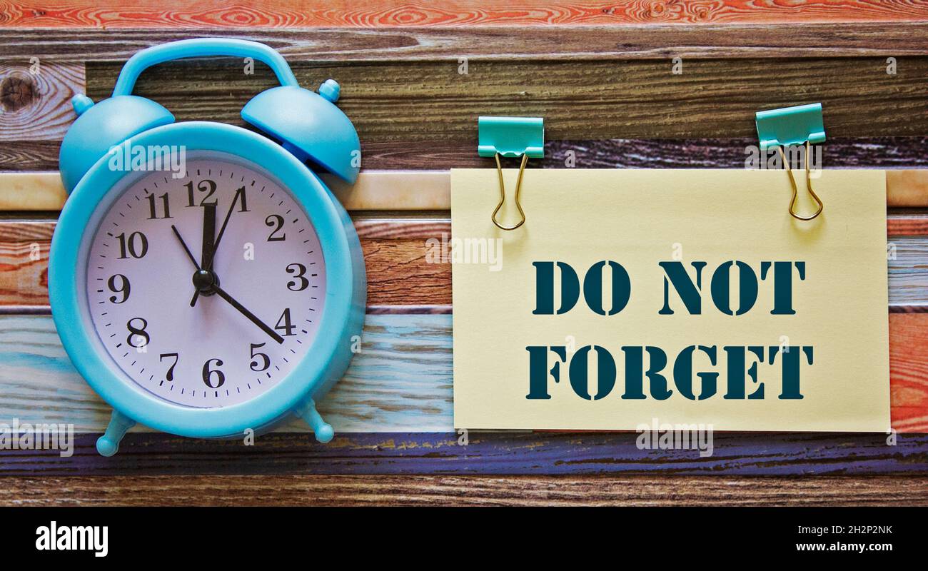 Do not forget anything text on sticky and sticker strips. Clock on wooden background Stock Photo