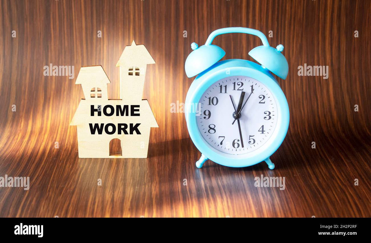 On the office table stands a wooden house with the text WORK HOME. Stock Photo
