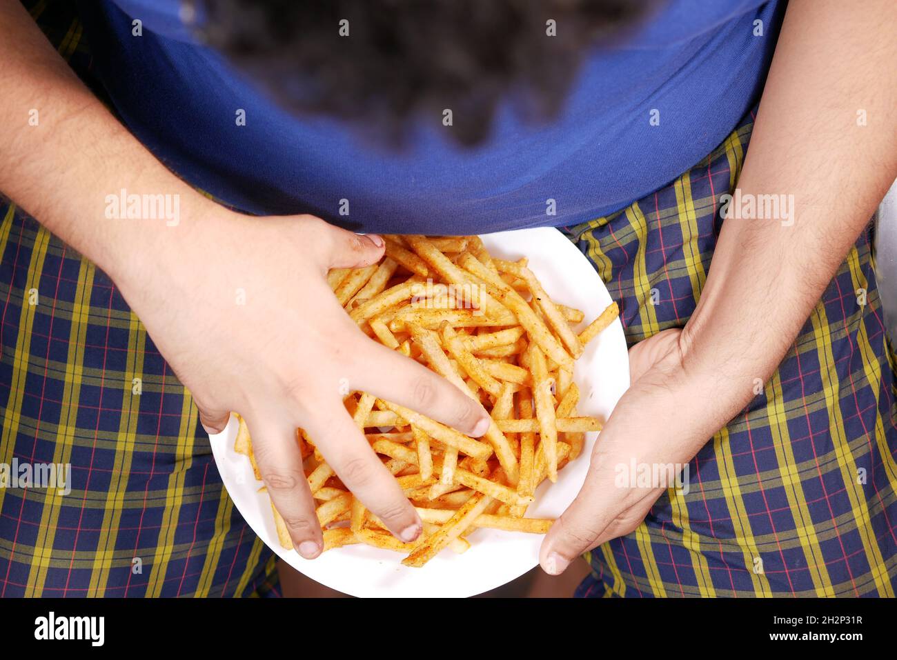 top view of a fat man hand pick french fries  Stock Photo
