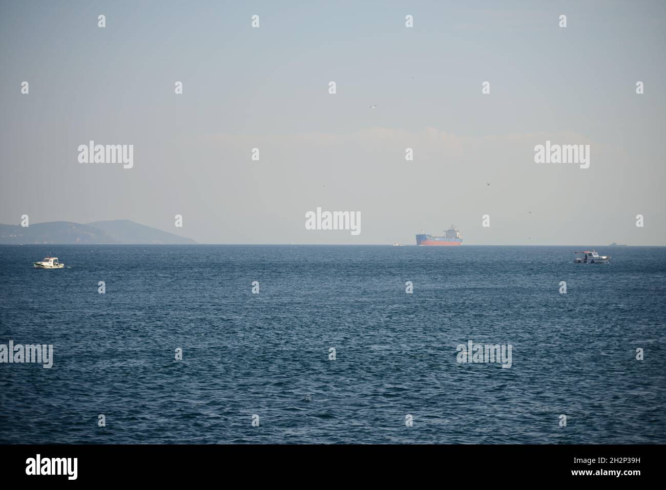 Misty spring day at a beach with boats hovering over the wavy sea ...
