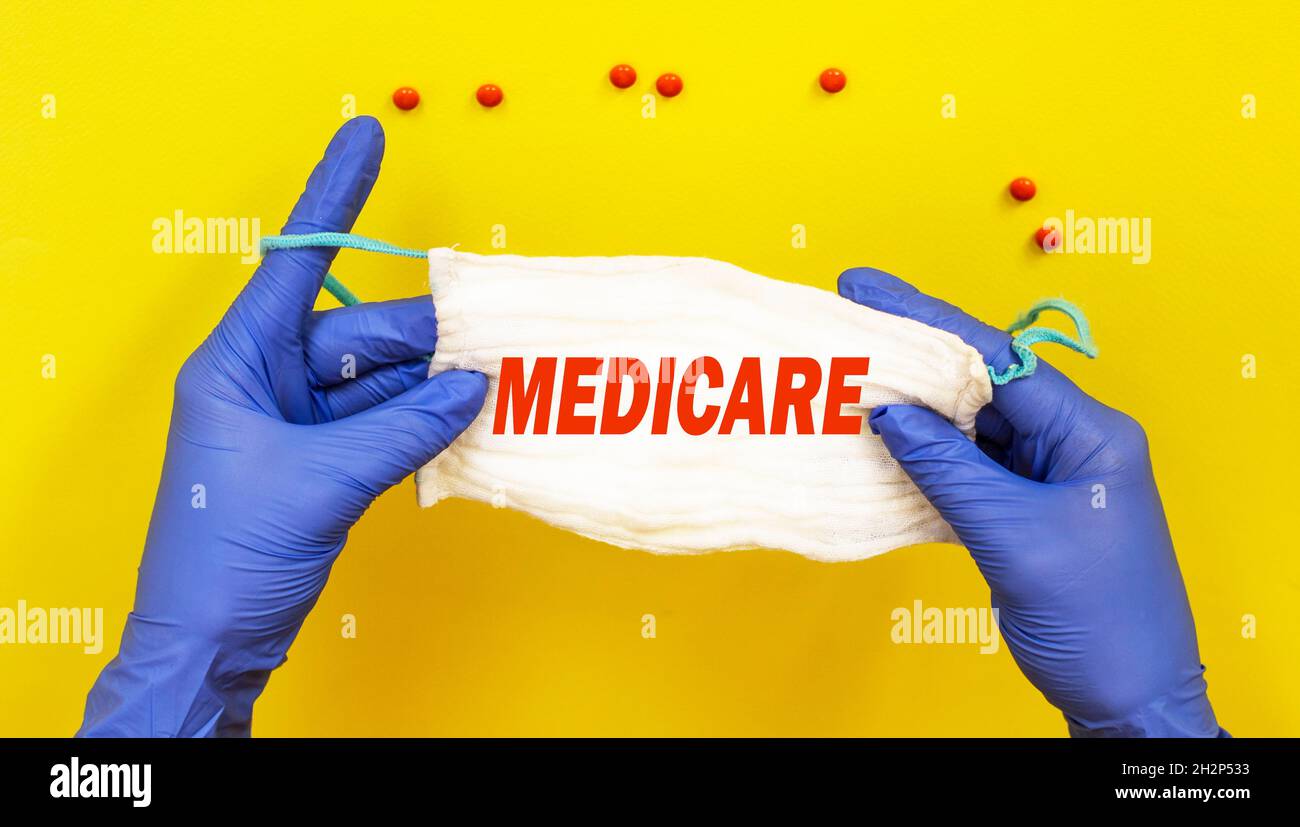 Doctor, woman holding a mask with the text MEDIGAP on a yellow background, near a pill. Medical concept. Stock Photo