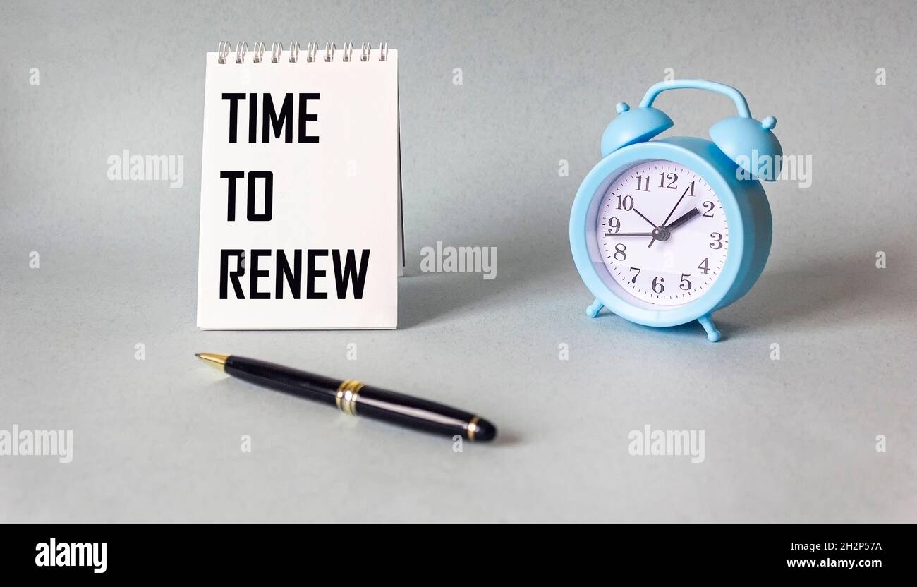 On a light background, a notebook with the inscription TIME TO RENEW, next to an alarm clock and a pen. Stock Photo
