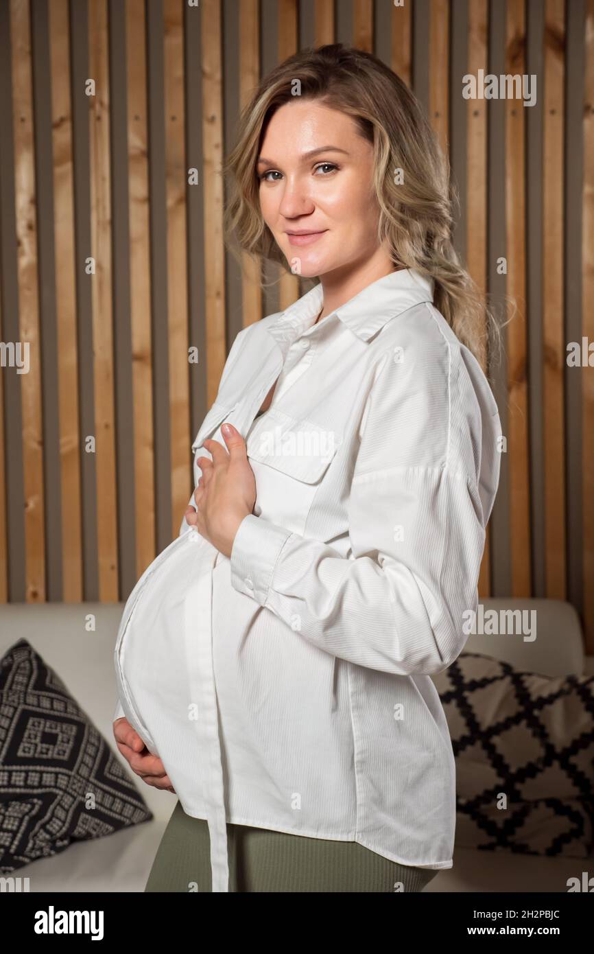 Beautiful pregnant woman hugs belly and smiles happily Stock Photo - Alamy