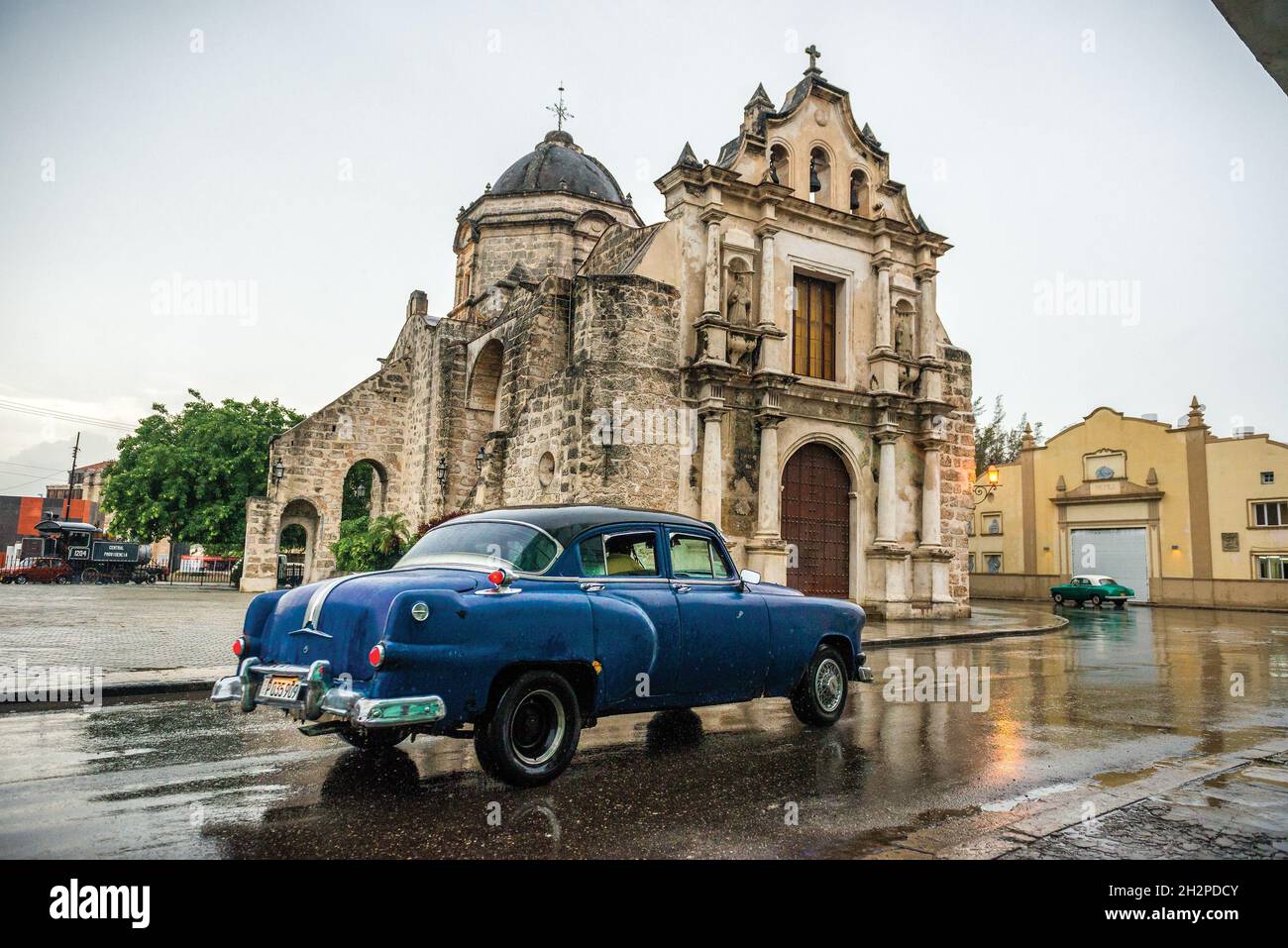 LA HABANA, CUBA - Apr 15, 2019: A classic Pontiac on a wet asphalt passing by Iglesia de San Francisco Paula in Havana, Cuba Stock Photo