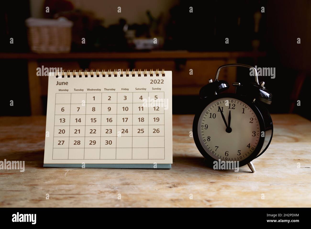 June 2022 calendar and black vintage clock on wooden table Stock Photo