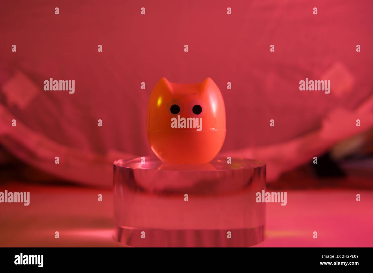 plastic owl toy on the glass cylinder the color background Stock Photo