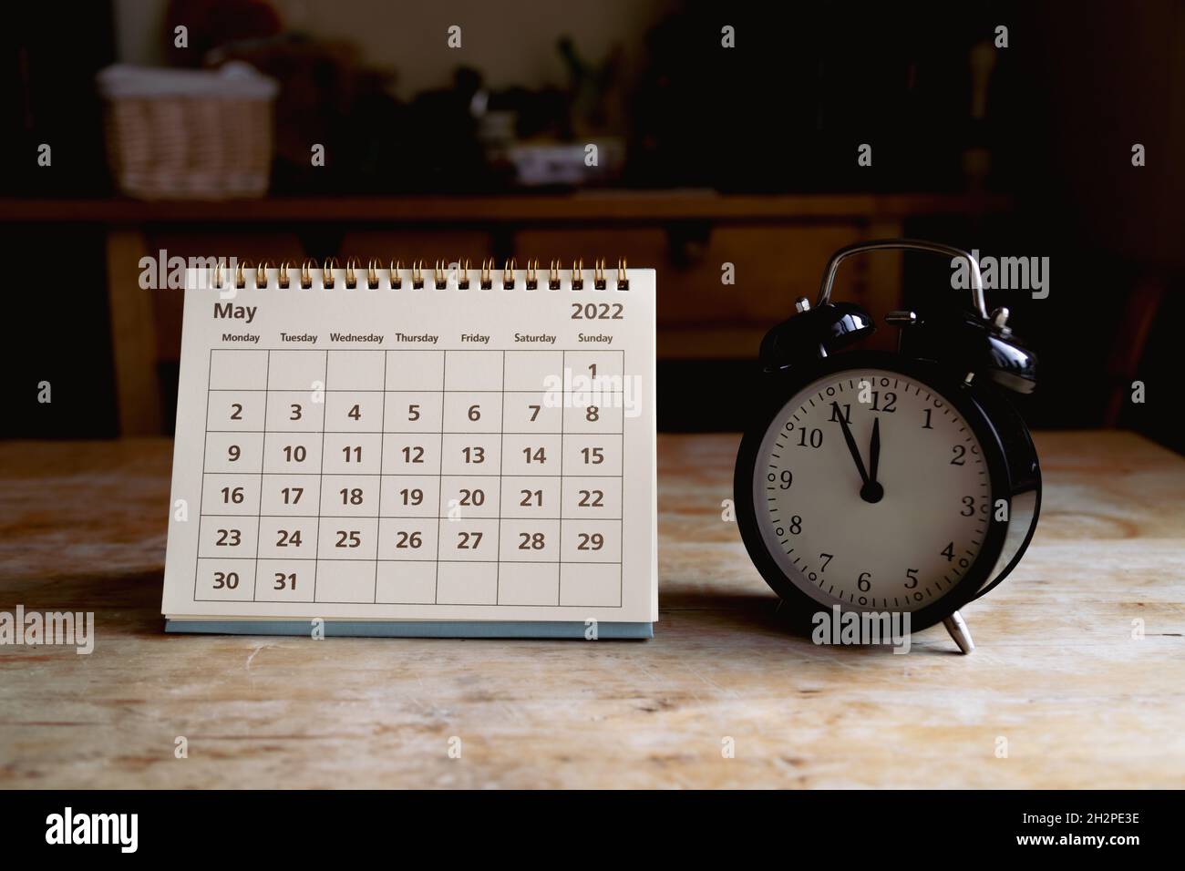 May 2022 calendar and black vintage clock on wooden table Stock Photo