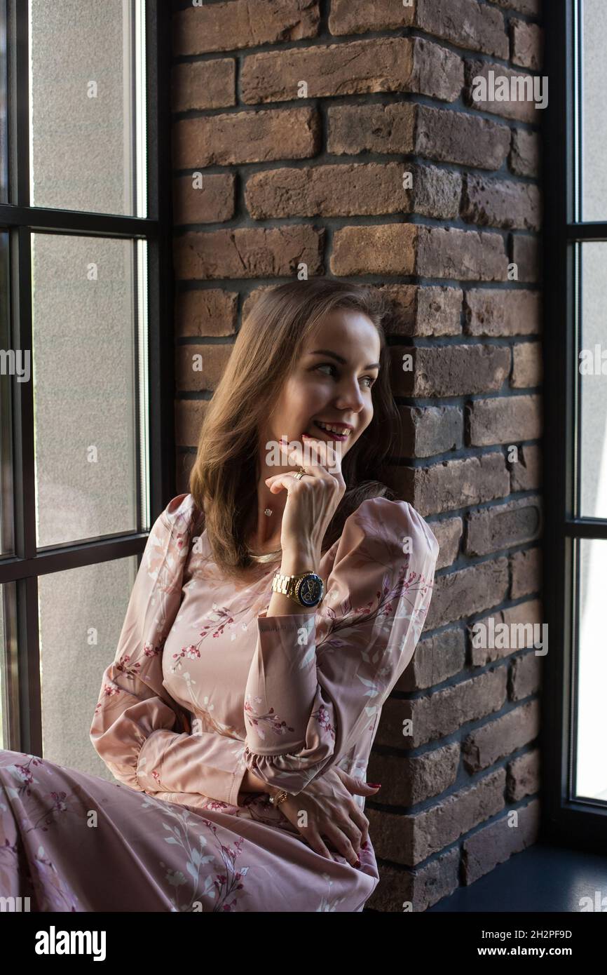 Beautiful young woman in pink dress sits on the windowsill Stock Photo ...