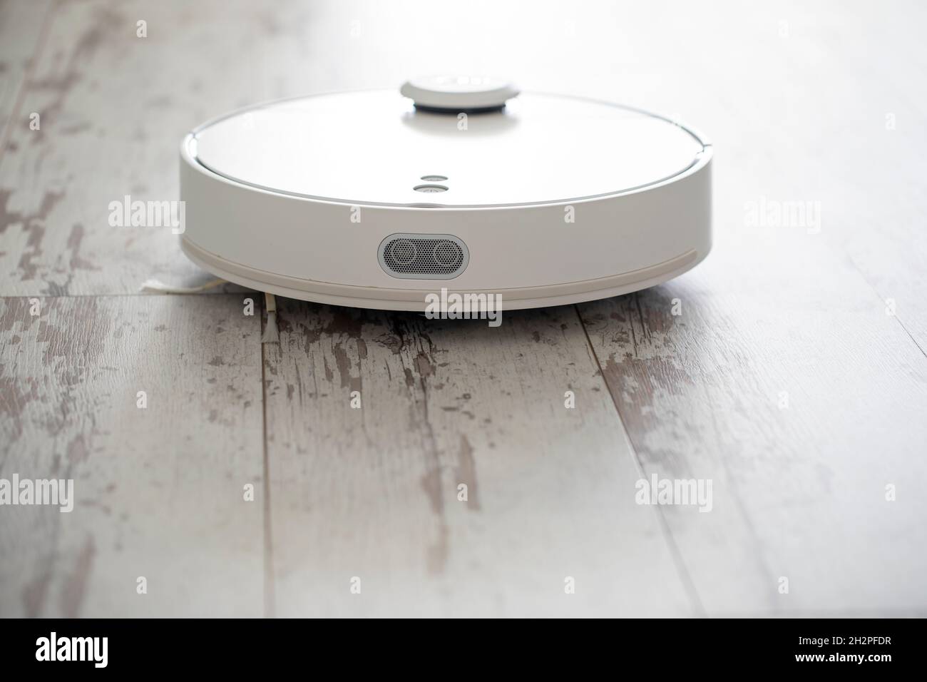 white robotic vacuum cleaner. The robot is controlled by voice commands