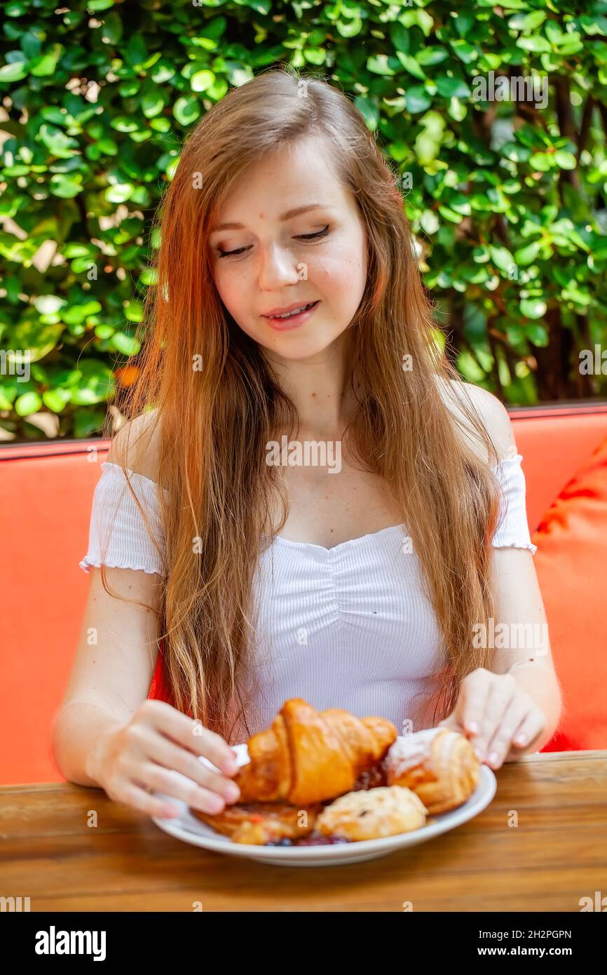 Young Beautiful Woman Enjoy Breakfast, Eat Fresh Bakery in Open-air Restaurant Stock Photo