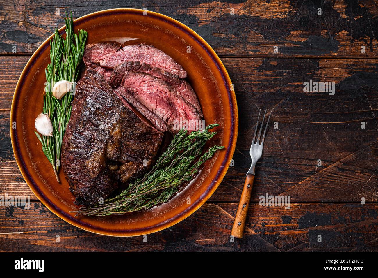 Roasted hanger or Onglet sliced beef meat steak on a rustic plate with  cleaver. Dark wooden background. Top View. Copy space Stock Photo - Alamy