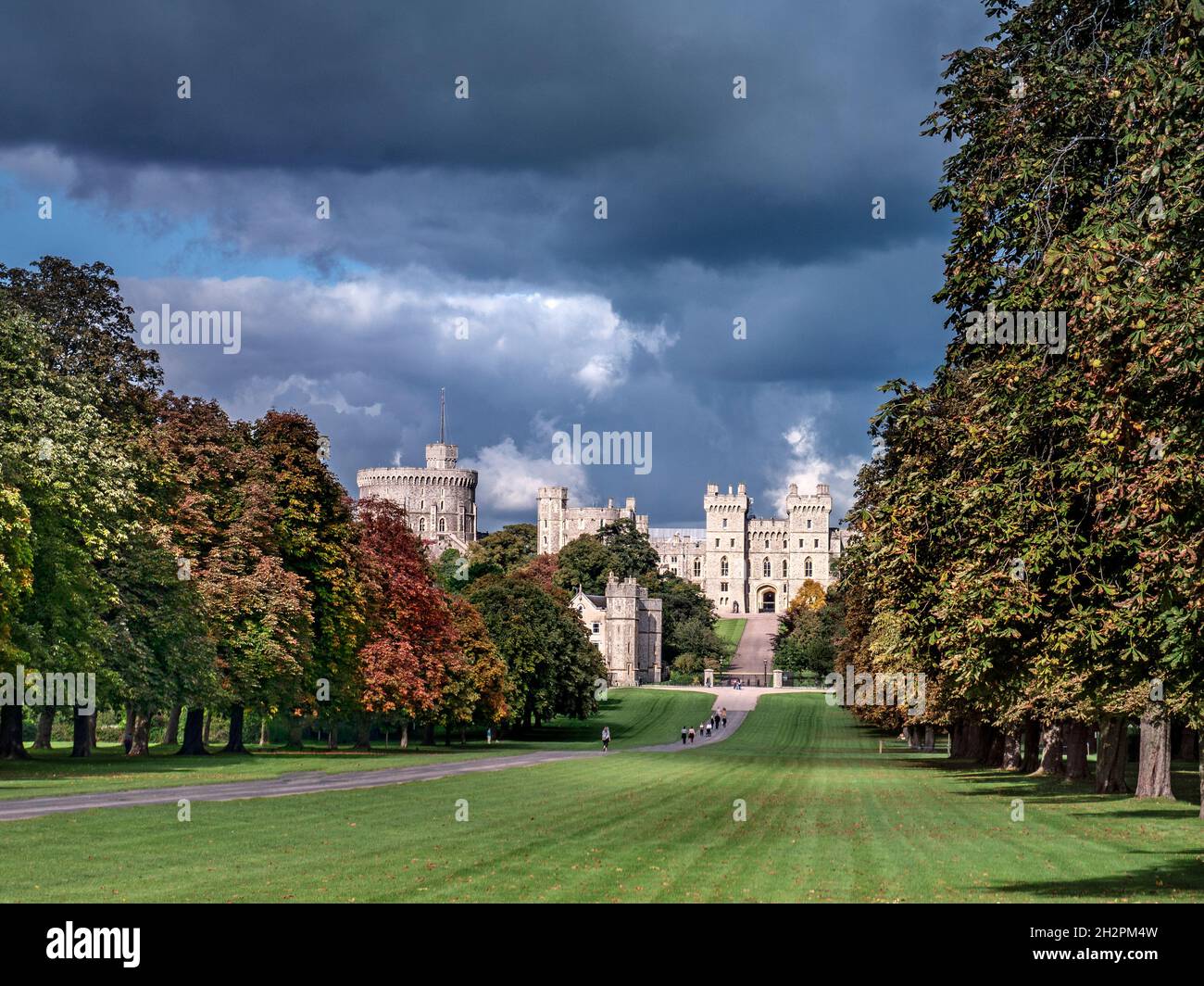 Windsor Castle viewed down the Long Walk with walkers, in autumnal colour with dramatic shafts of autumn sunlight and brooding sky Berkshire UK Stock Photo