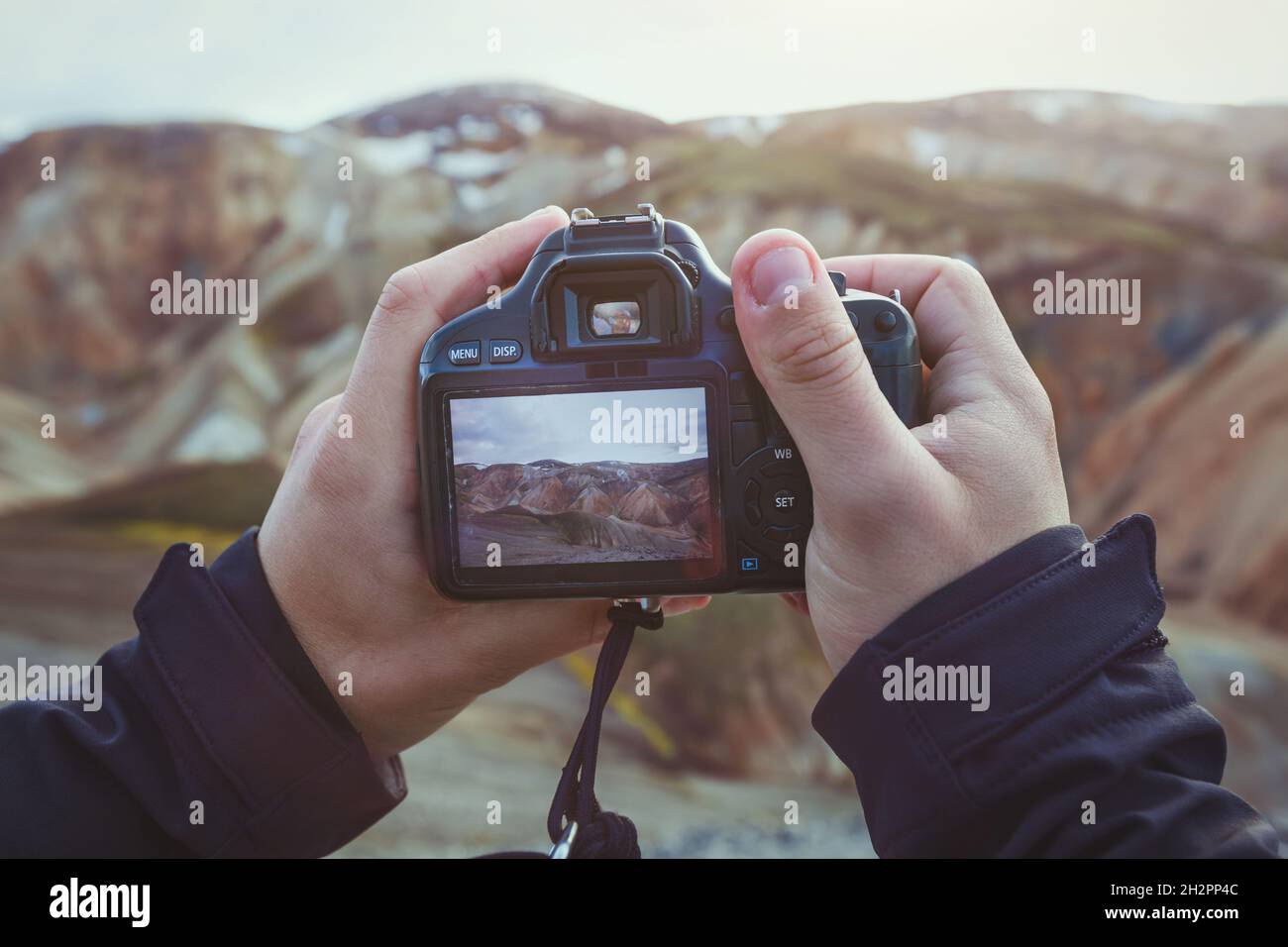 landscape travel photographer hands holding camera, taking photo of mountains Stock Photo