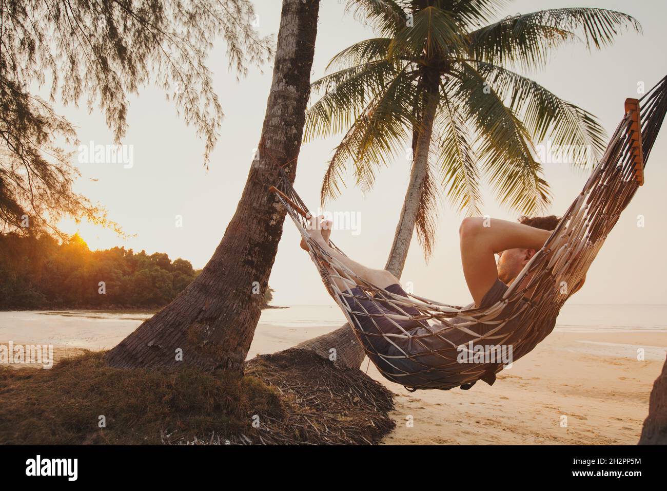 tourist relaxing in hammock on tropical beach with coconut palm trees, relaxation and leisure tourism Stock Photo